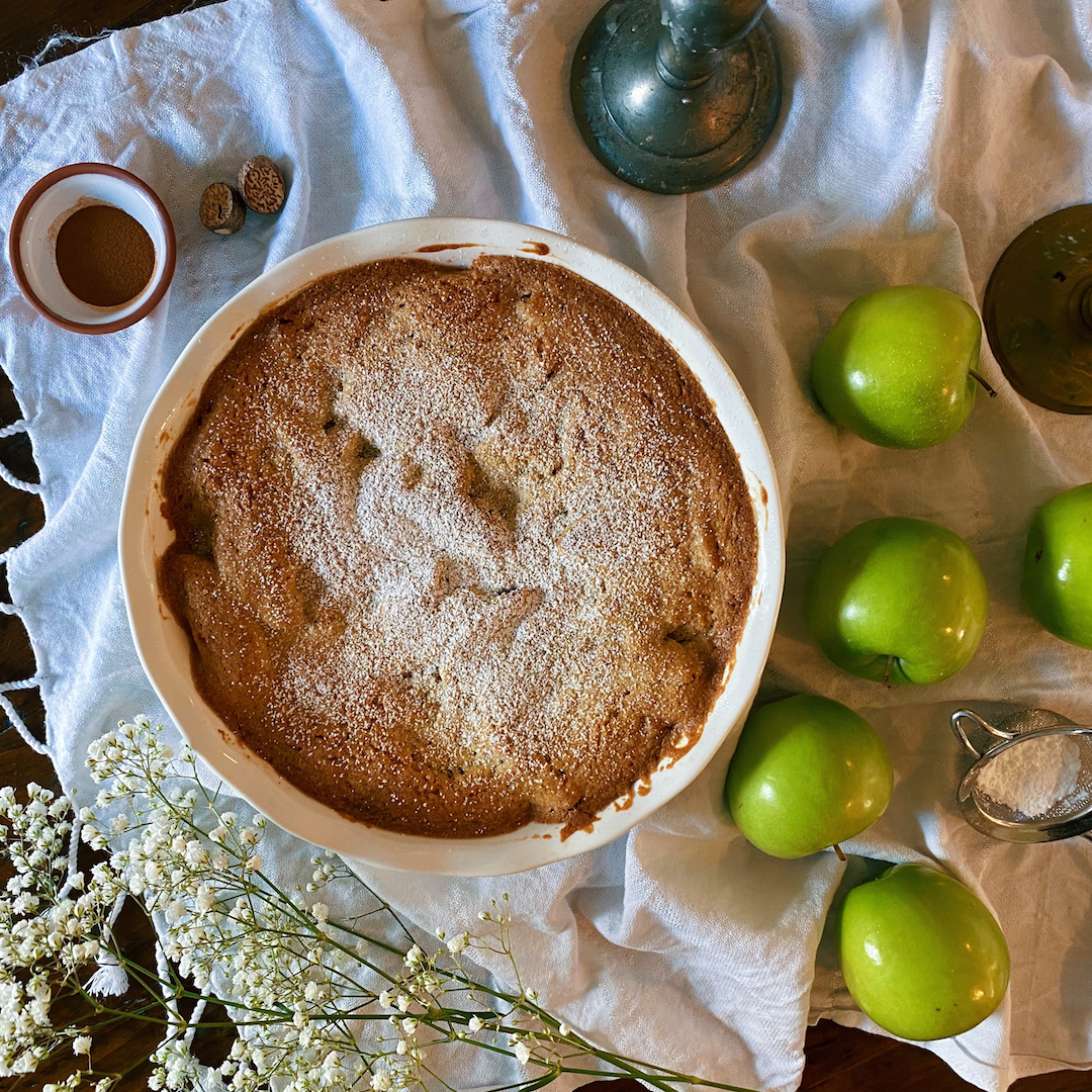 apple cobbler pie on a white cloth next to green apples