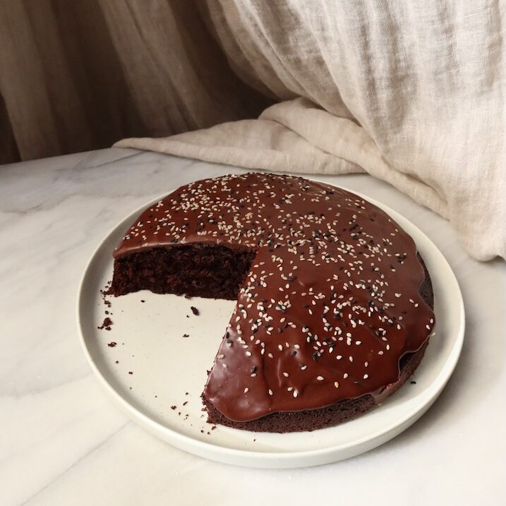 chocolate cake, with a slice removed, on a beige plate