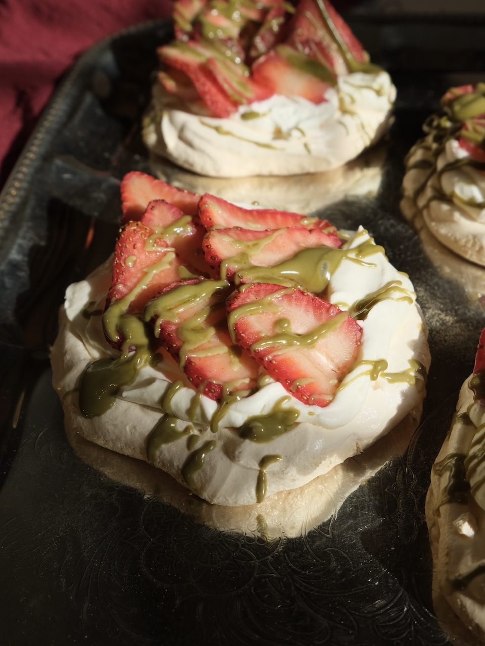 mini pavlovas topped with strawberries and pistachio cream