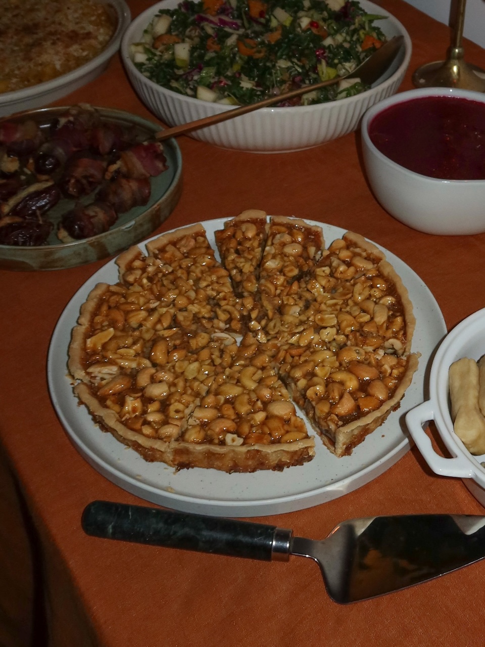 cashew tart on an orange table with other dishes